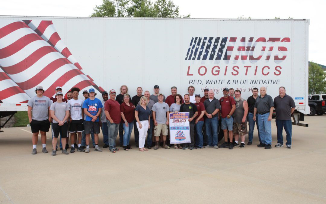 group of nots logistics employees posing in front of red white and blue initiative semi truck